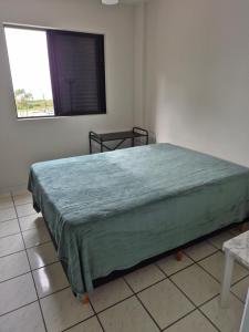 a bedroom with a bed with a green blanket on it at Caioba Apto Confortavel in Matinhos +16 photos