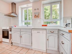 a white kitchen with white cabinets and windows at Farmhouse in Boncourt with Private Garden in Sainte-Preuve