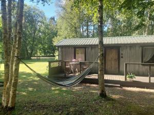 a hammock in front of a cabin in the woods at Eedu suvila in Saaremaa