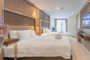 ein Hotelzimmer mit zwei Betten und einem Fernseher in der Unterkunft Vanko International Hotel Pattaya Central in Pattaya