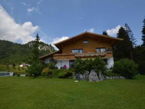 a wooden house with a green lawn in front of it at Apartment in Hinterbichl near Ski Bus in Reutte