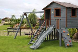 a playground with a slide and a house at Lauras Apartment in Bauska