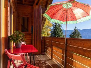 Ein roter Tisch und ein Stuhl auf einer Veranda mit einem Sonnenschirm in der Unterkunft Wohnung in St Stefan nahe Nassfeld Skigebiet in Tratten