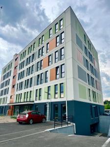a building with a red car parked in a parking lot at Olive&Air Haven in Cluj-Napoca