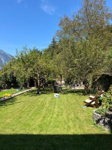 a park with trees and a picnic table in the grass at Schweizerhaus Glarus - Historisch & Stilvoll mit Garten in Ennenda