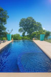 a swimming pool with blue water and trees in the background at Blue Samui Ocean Villa - 3 Large Ensuite Bedrooms - Private Pool, Jacuzzi Villa & Car with driver - Near Four Seasons - Ocean & Mountains Views in Nathon Bay