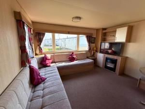 a living room with a couch with pink pillows at Superb 8 Berth Caravan At St Osyth Beach Holiday Park, Essex Ref 28010Mv in Clacton-on-Sea