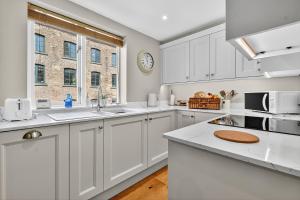 a kitchen with white cabinets and a window at 46 Tannery Mews in York