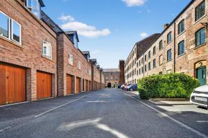 an empty street between brick buildings with cars parked at 46 Tannery Mews in York