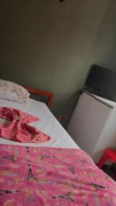 a bedroom with a bed with a pink blanket at hotel larenaa in Sete Lagoas