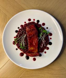 un piatto bianco con un pezzo di carne e salsa di mirtilli rossi di Restaurant Golden Fish Baku a Baku