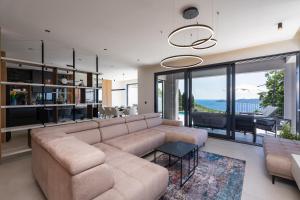 a living room with a sectional couch and a table at Villa Blue Sunset - Stunning Sea View Luxury Villa with Private Heated Pool in Brsečine
