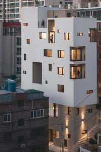 een wit gebouw met ramen bovenop een gebouw bij CatNap Guesthouse in Busan