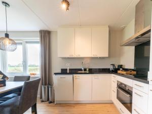 a kitchen with white cabinets and a dining table at Holiday home in Scherpenisse in Scherpenisse