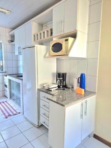 a kitchen with white cabinets and a microwave at Hospede-se bem em Salinas in Salinópolis