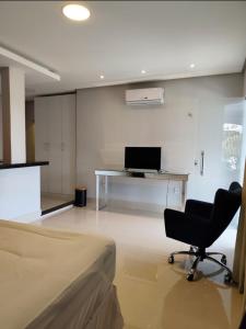 a room with a bed and a desk with a computer at Kitnet in Belém