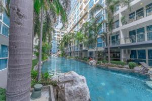 einem Pool in der Mitte eines Gebäudes mit Palmen in der Unterkunft Vanko International Hotel Pattaya Central in Pattaya