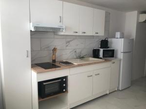 a kitchen with white cabinets and a sink and a microwave at Appartement au calme 4 personnes in Saint-Paulet-de-Caisson