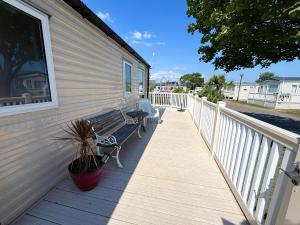 a person sitting on a bench on a porch at 6 Berth Caravan With Decking And Wifi At Suffolk Sands Holiday Park Ref 45040G in Felixstowe