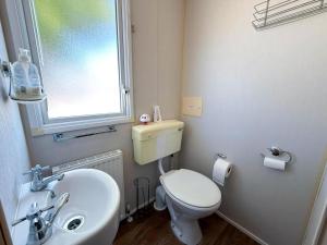 a small bathroom with a toilet and a sink at 6 Berth Caravan With Decking And Wifi At Suffolk Sands Holiday Park Ref 45040G in Felixstowe +18 photos