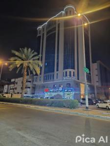 a large building with a palm tree in front of it at فندق مواسم العزيزية in Al ‘Azīzīyah