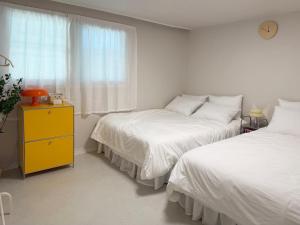 a bedroom with two beds and a yellow dresser at DMC Station,Airport Railroad,Hongdae 10 minutes,King size bed,Family, Group accommodation,JINJIN STAY,Air conditioning in each room in Seoul