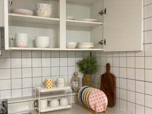 a kitchen with white cabinets and dishes on shelves at DMC Station,Airport Railroad,Hongdae 10 minutes,King size bed,Family, Group accommodation,JINJIN STAY,Air conditioning in each room in Seoul +23 photos
