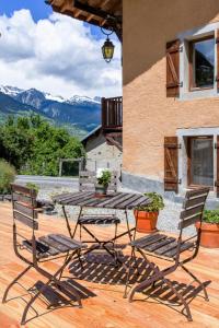 - une table en bois et 2 chaises sur la terrasse dans l'établissement Gite-Auberge de Montvilliers, à Aime