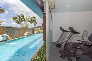 a fitness room with a swimming pool and exercise equipment at CHIC CONDO - Best mountain view near Karon beach in Karon Beach