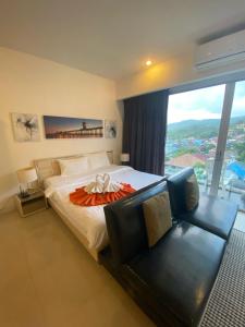a bedroom with a bed and a couch and a window at CHIC CONDO - Best mountain view near Karon beach in Karon Beach