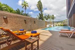 a patio with orange chairs and a swimming pool at CHIC CONDO - Best mountain view near Karon beach in Karon Beach