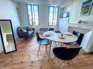 a living room with a table and chairs and a fireplace at Les Arcades - Mirande Centre in Mirande +5 photos