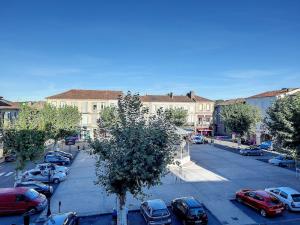 a city street with cars parked in a parking lot at Les Arcades - Mirande Centre in Mirande