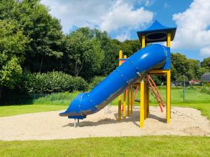 a playground with a blue slide in the sand at Dat Reethus Helfsholm in Klamp
