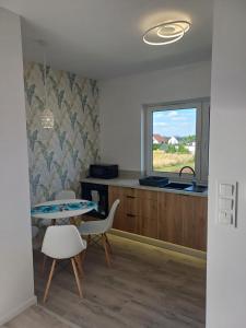a kitchen with a table and chairs and a sink at Apartamenty Jasna, Mieszkania in Ostrów Wielkopolski