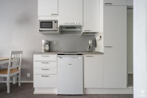 a white kitchen with a sink and a microwave at Holiday in Lapland - Ylläs Sivulantie 106 in Äkäslompolo