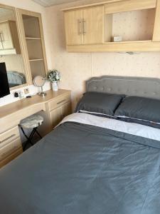 a bedroom with a bed and a desk and a tv at Caravan by the sea in Gristhorpe +2 photos