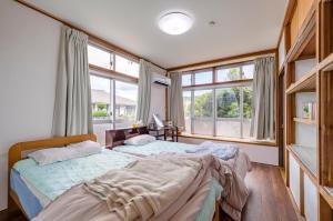 two beds in a room with two windows at サフラン in Kumejima