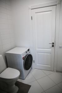 a bathroom with a toilet and a washing machine at Lauras Apartment in Bauska