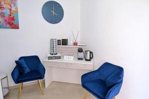two blue chairs and a desk with a clock on a wall at Noemi House & Rooms in Novara