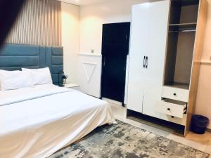 a bedroom with a white bed and a black cabinet at Emily Apartment in Lagos