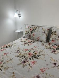 een bed met een bloemdekbed en 2 kussens bij Noemi House & Rooms in Novara