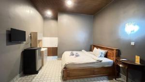 a small bedroom with a bed and a television at Mother’s House in Battambang