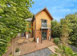 a house with a deck with chairs and trees at Modern Retreat in Kent Countryside in Tonbridge