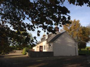 a white house with a chimney on top of it at Eastwood Cottage in Turriff