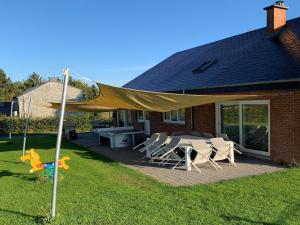 a patio with a table and chairs under a canopy at Modern villa in Rochefort close to the horses in Wavrielle +33 photos