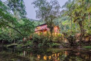 ein Haus im Wald neben einem Fluss in der Unterkunft Camburi 5 quartos com piscina natural in Camburi