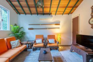 ein Wohnzimmer mit orangefarbenen Möbeln und einem Flachbild-TV in der Unterkunft Camburi 5 quartos com piscina natural in Camburi