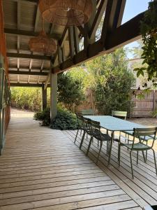 einen Tisch und Stühle auf einer Holzterrasse in der Unterkunft Maison de vacances à Petit Piquey, entre Bassin et Océan in Lège-Cap-Ferret