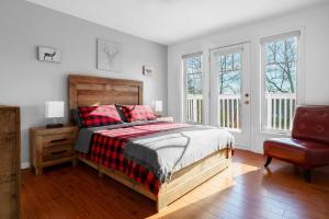 a bedroom with a bed and a chair and windows at Chalet De l'Escapade hot tub Lakeview kayaks in Entrelacs